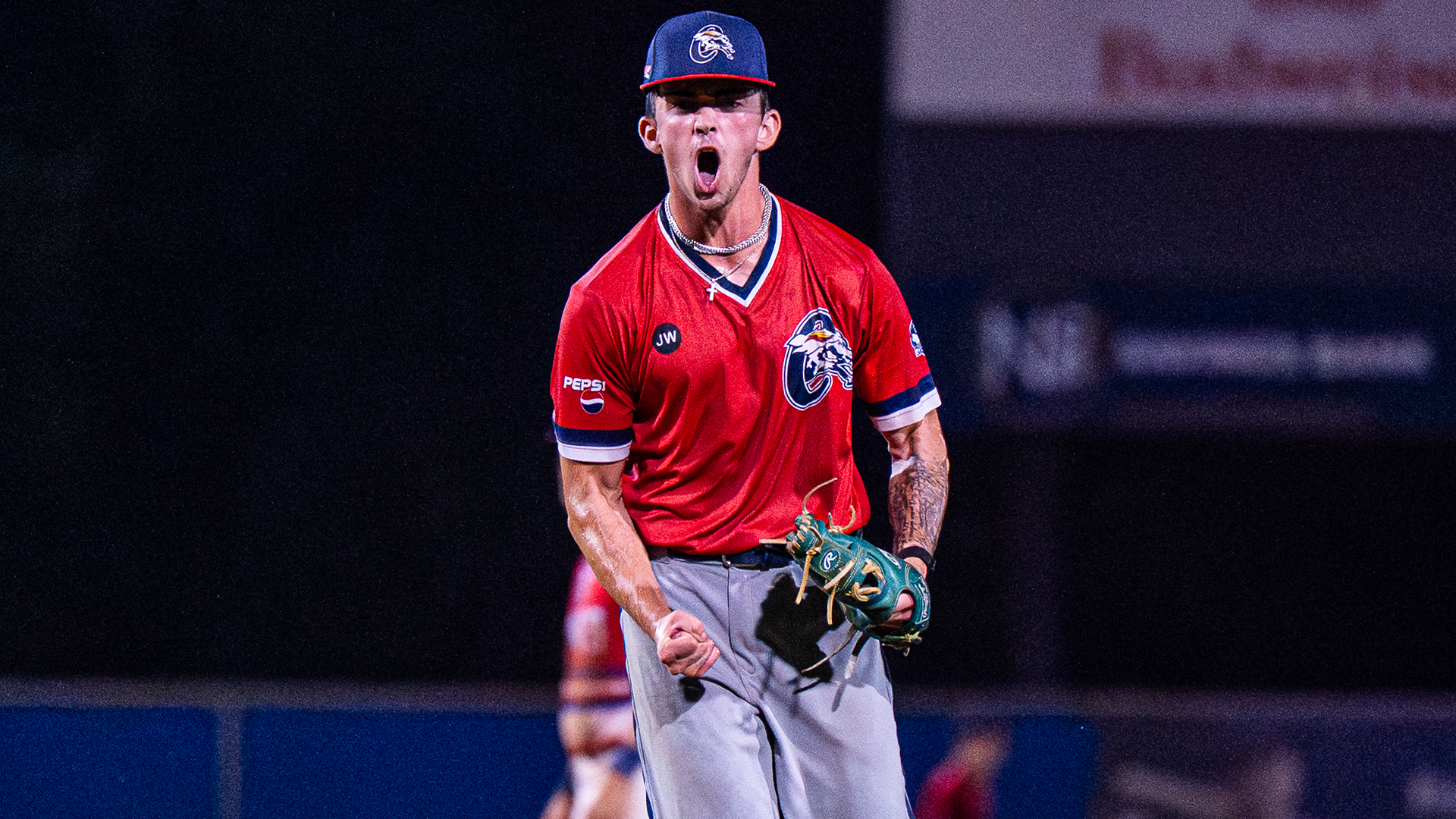 The photo shows Cameron Birch celebrating with a clenched fist and his mouth open from a celebratory yell after striking out a batter last summer at Champion City. He's wearing a navy blue cap with a red bill, a red jersey with the Paints logo and gray pants.